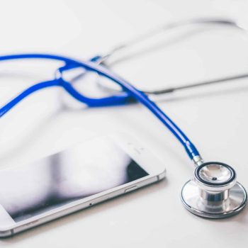 a phone and a stethoscope on a table. a phone and a stethoscope on a table.