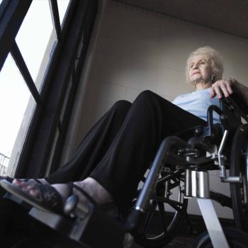 a woman in a wheel chair looking out a window. a woman in a wheel chair looking out a window.