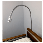 A flexible desk lamp, #15395, overhanging a wooden bedside table against a grey wall.