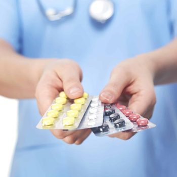 a person in a blue shirt holding a contraption and pills.