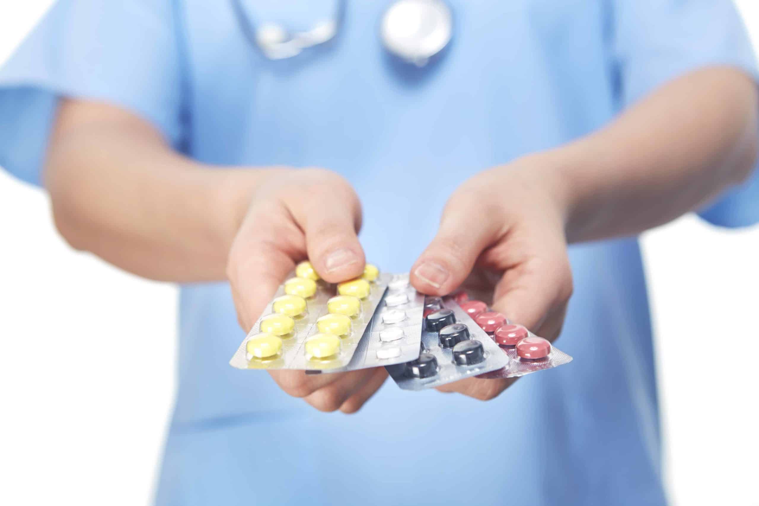 a person in a blue shirt holding a contraption and pills.