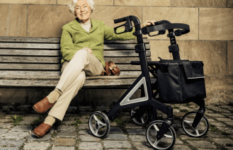 a woman sitting on a bench next to a hand cart.