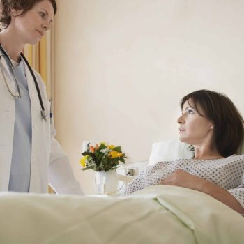 a woman in a hospital bed talking to a doctor.