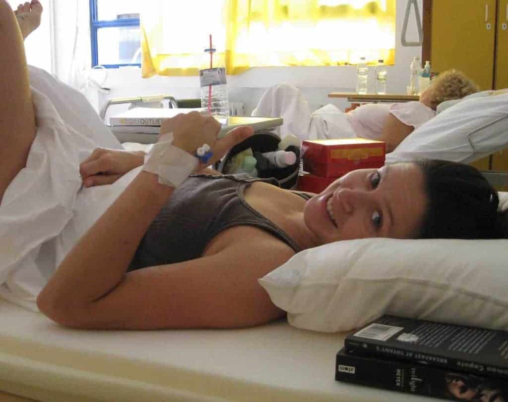 a woman laying in a hospital bed with an iv in her hand.