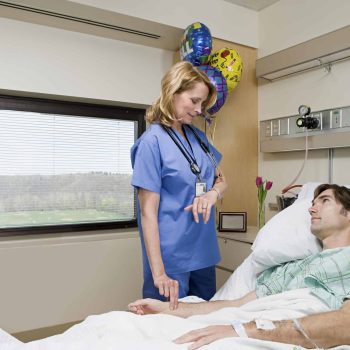 a woman standing next to a man in a hospital bed. a woman standing next to a man in a hospital bed.