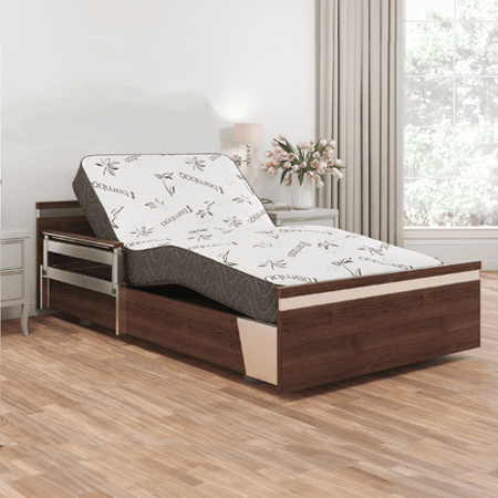 The SonderCare Aura™ Wide Hospital Bed - Extra Wide Home Hospital Bed, featuring an adjustable wooden frame and mattress in a partially raised position, with floral decor on the side table and a large window adorned with closed curtains in the background, creates an atmosphere of tranquility while offering added comfort through its extra wide design.