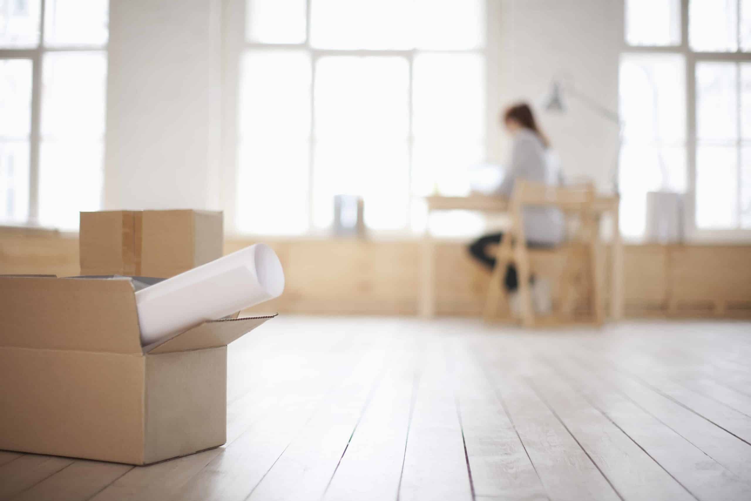 a woman sitting at a table in a room with boxes on the floor.