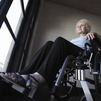 a woman in a wheel chair looking out a window.